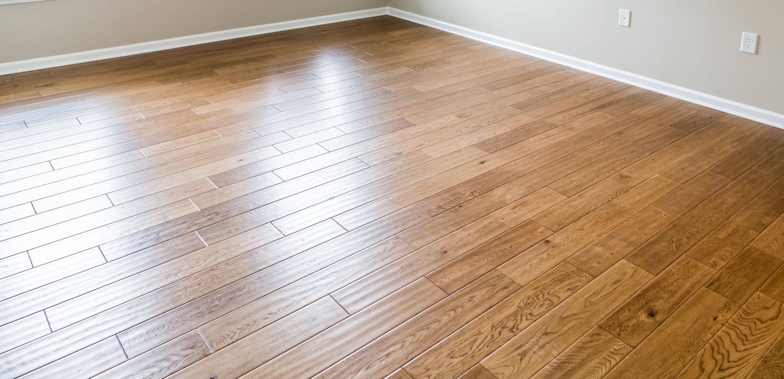 A polished hardwood floor in a well-lit room, showcasing its smooth texture and natural wood grain