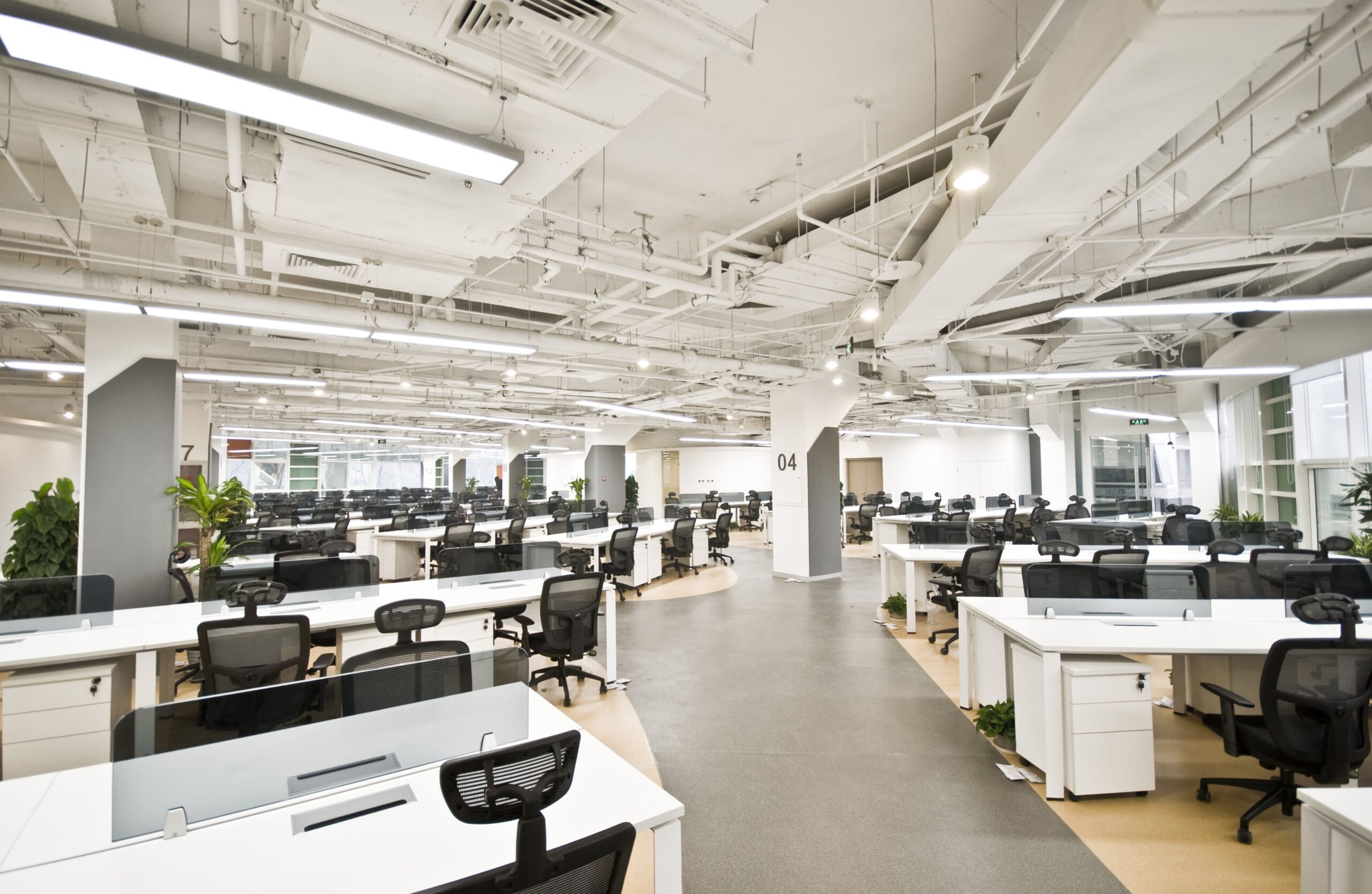 A spacious office featuring multiple desks and chairs arranged throughout the room