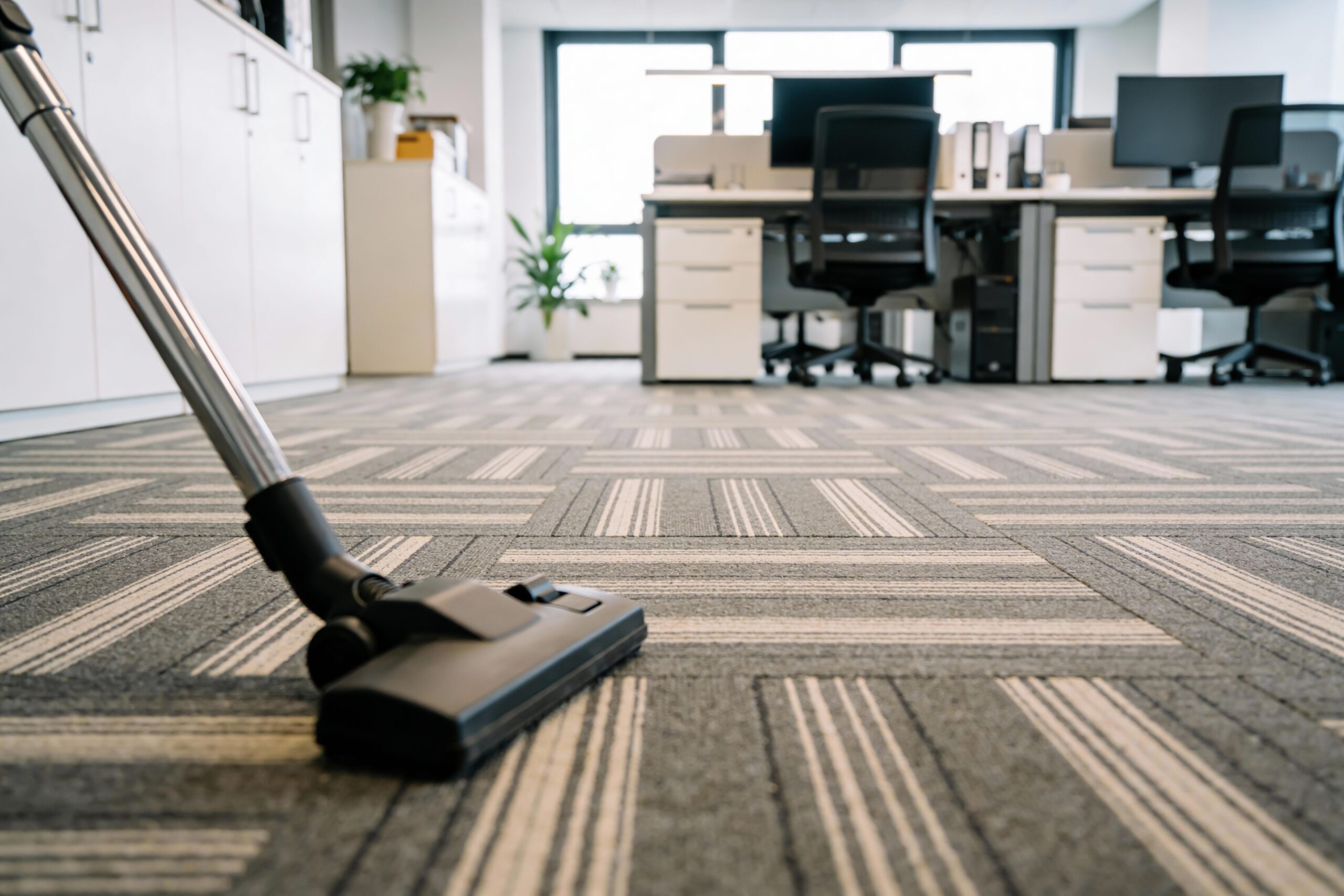 A vacuum cleaner is actively cleaning a carpet in a modern office setting